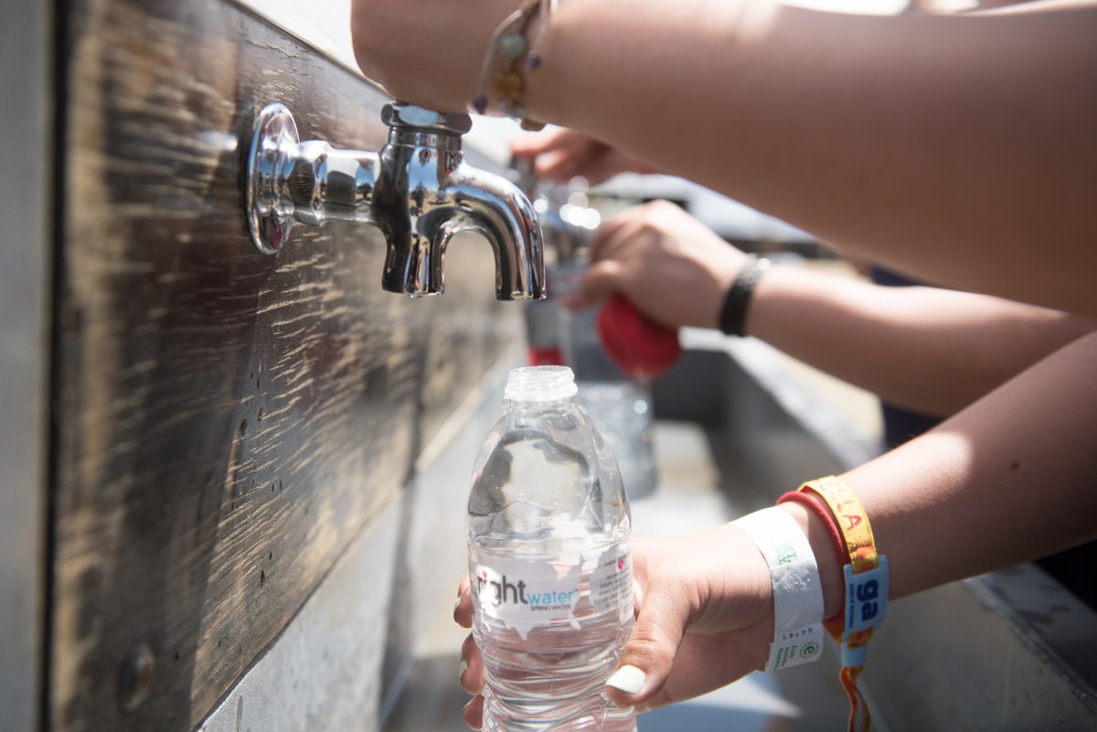 Close up of a festival goer refilling her plastic water bottle with water