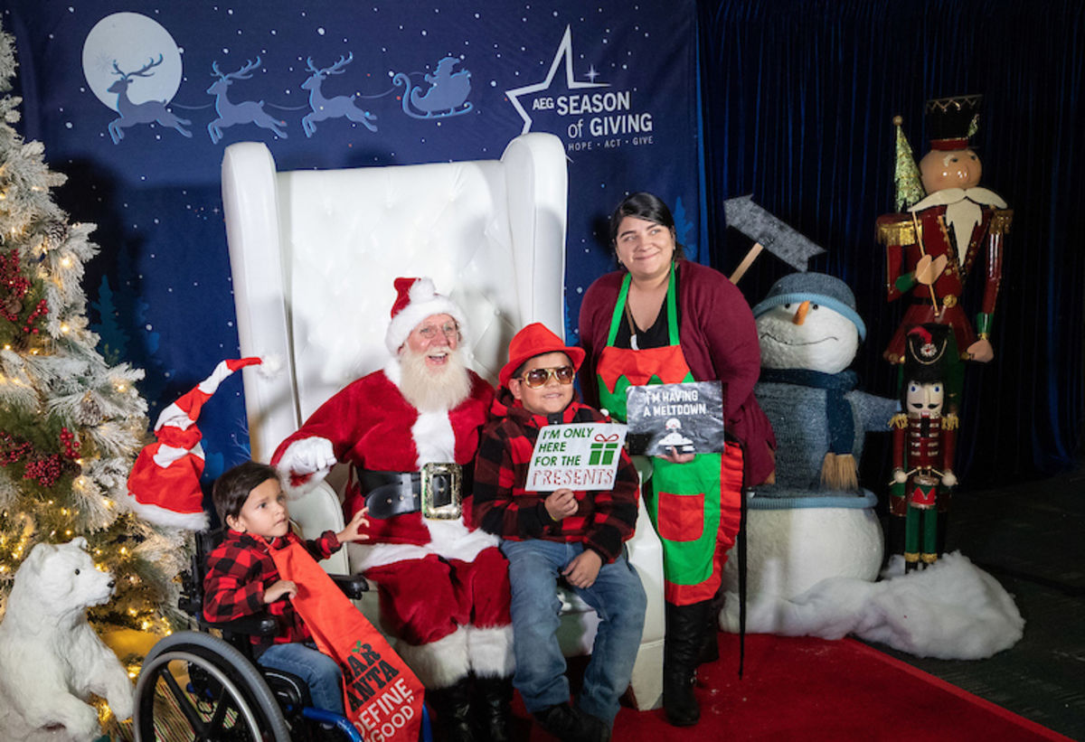 Two boys and a mother pose with Santa during AEG's annual Community Holiday Party at the Los Angeles Convention Center. 
