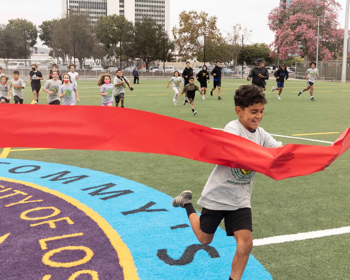 Local soccer youth run through the red ribbon on a soccer field to commemorate the grand opening. 