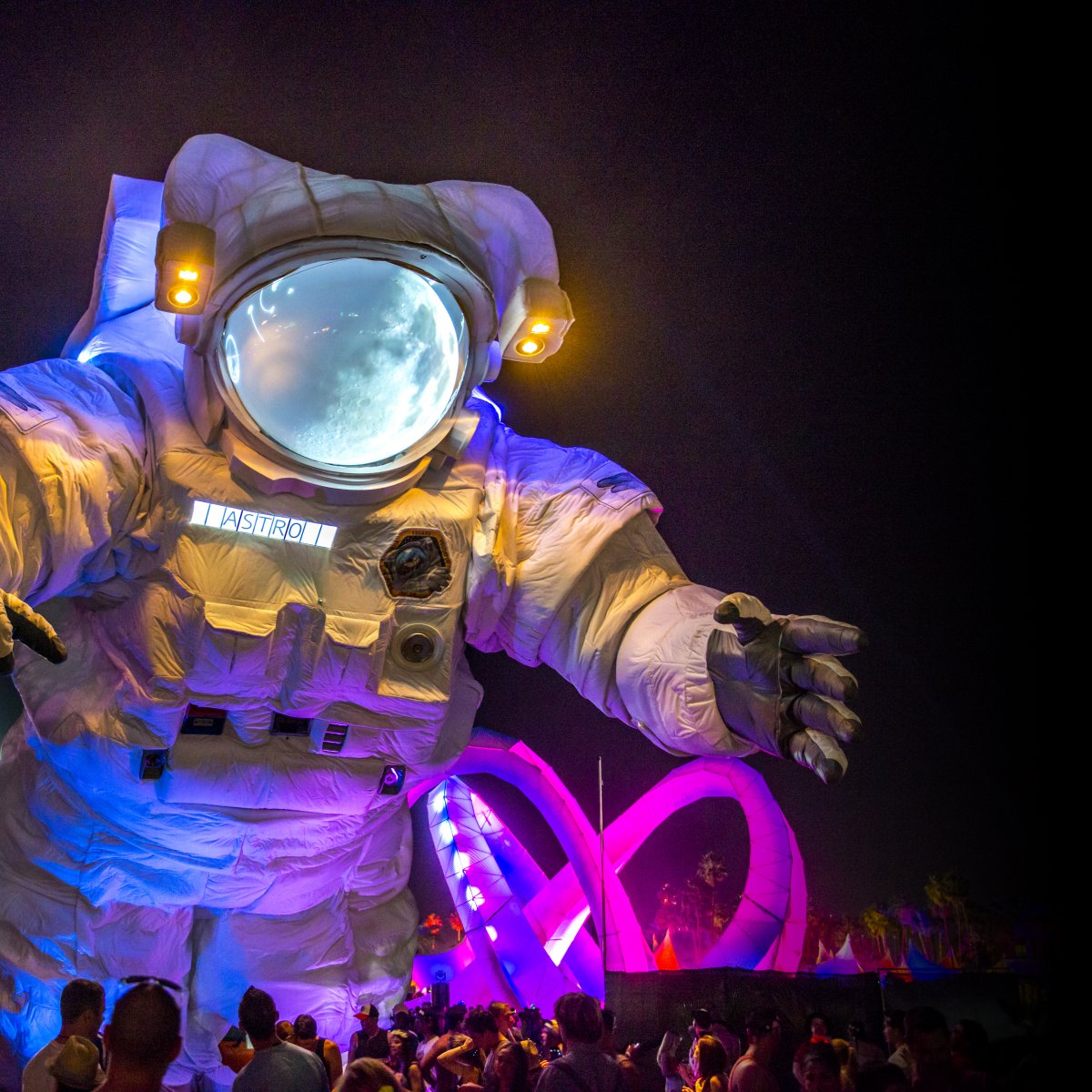 Image of a large astronaut art installation with a ferris wheel in the background during night time