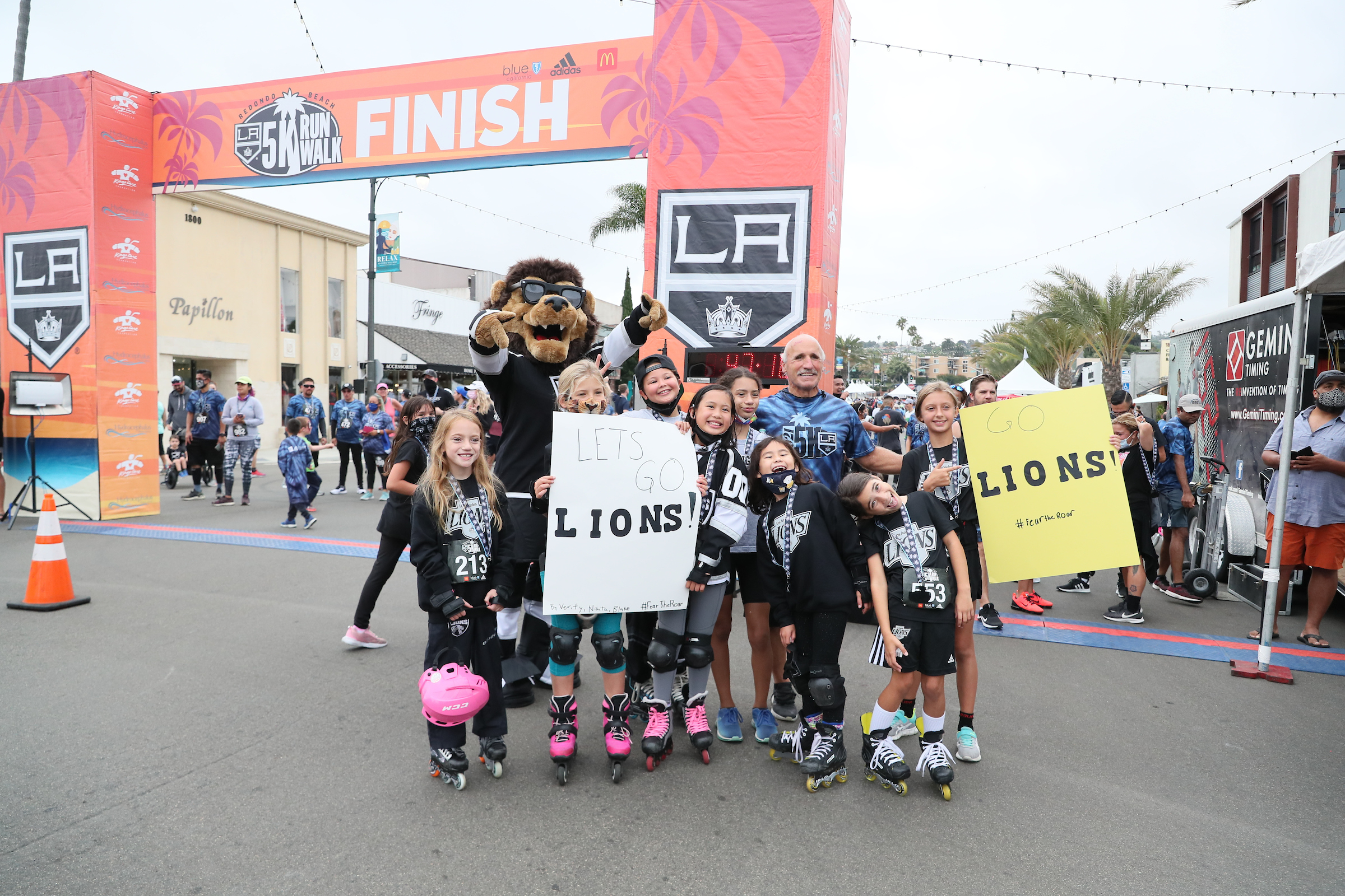 Members of the LA Lions girls hockey team cheer on runners with LA Kings mascot Bailey during the LA Kings 5K. 