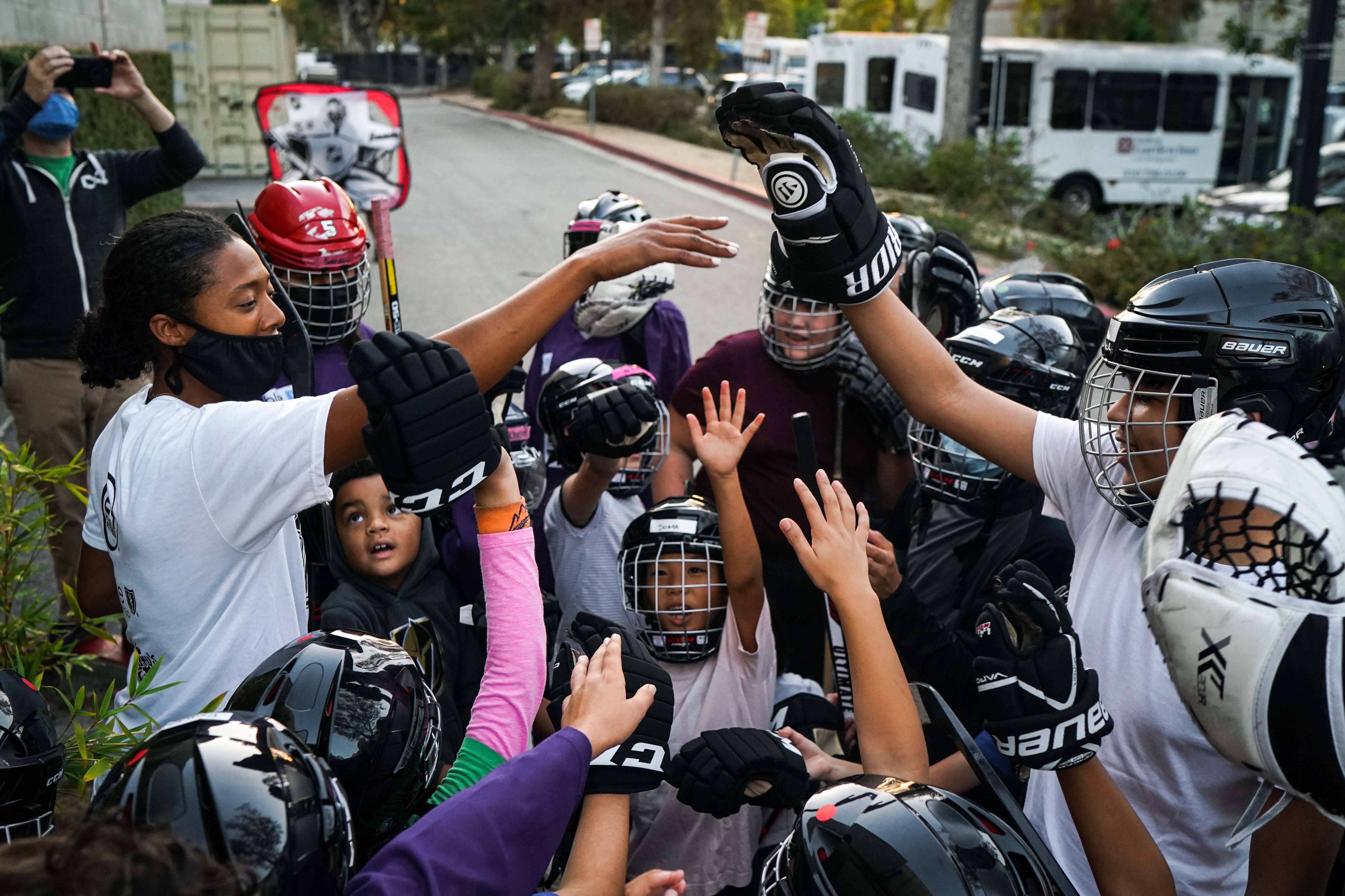 LA Kings pro scout Blake Bolden (left) brings it in with a group of kids after ball hockey practice. 