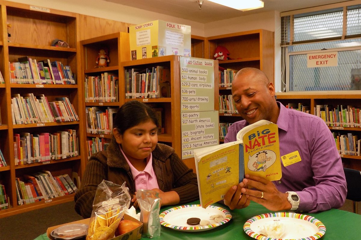 Employee reading to a student in a library