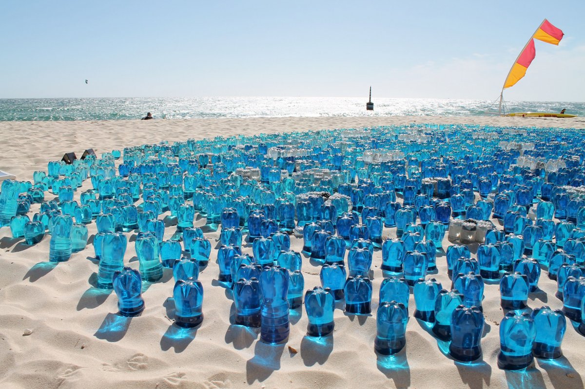 Hundreds of blue water bottles used as art upside down in the sand on the beach