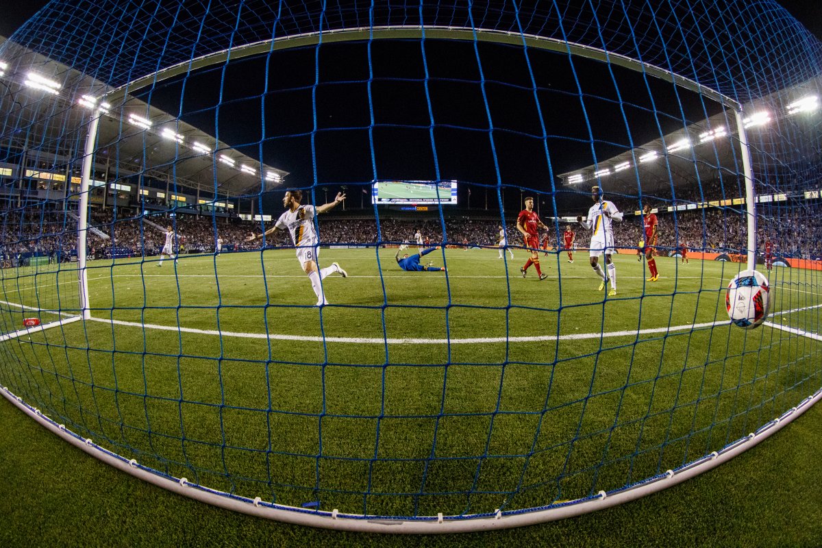 Galaxy player scoring a goal, image taken from behind net with LED lights shining down