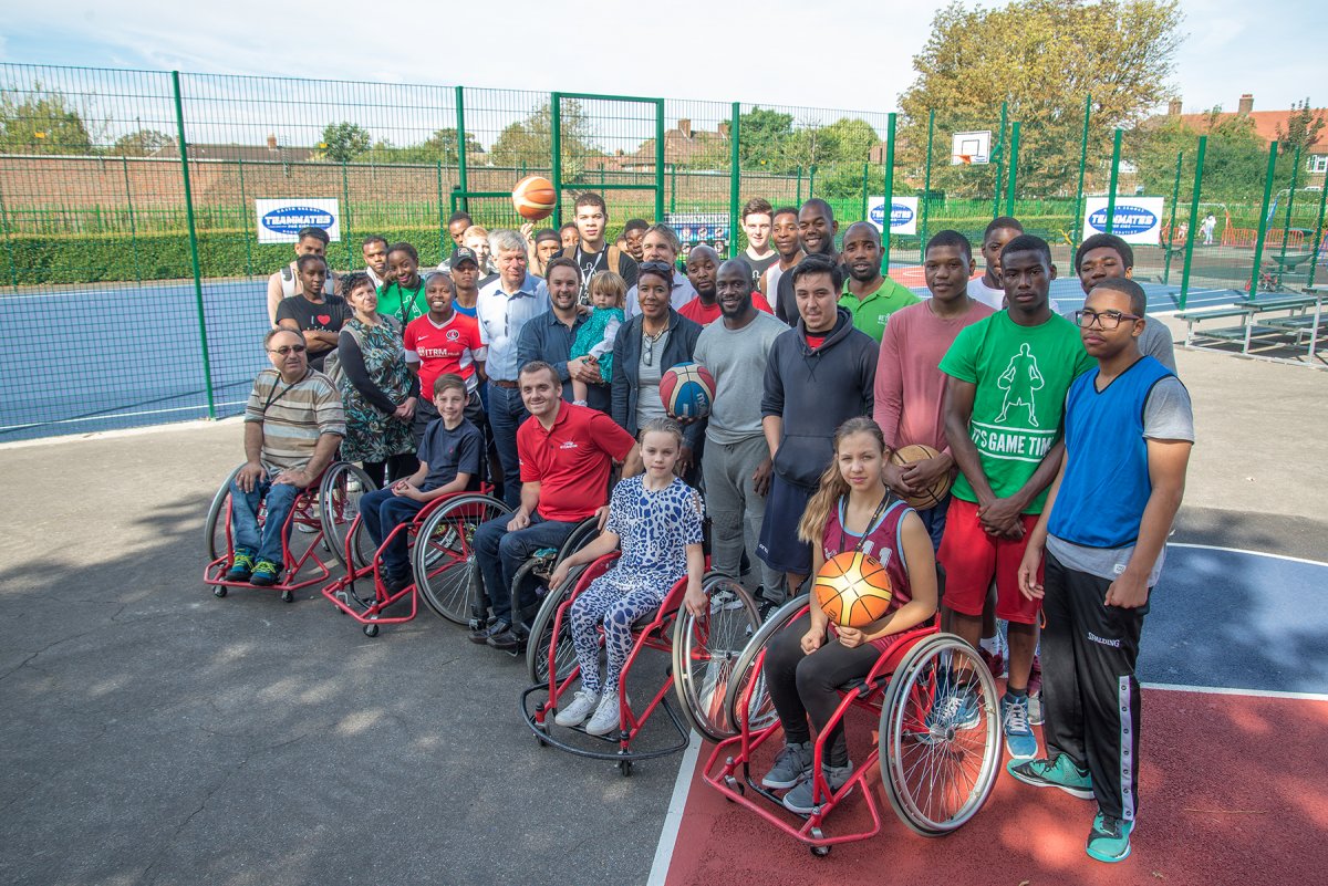 A group of employees on a basketball court with individuals in wheelchairs for the special olympics