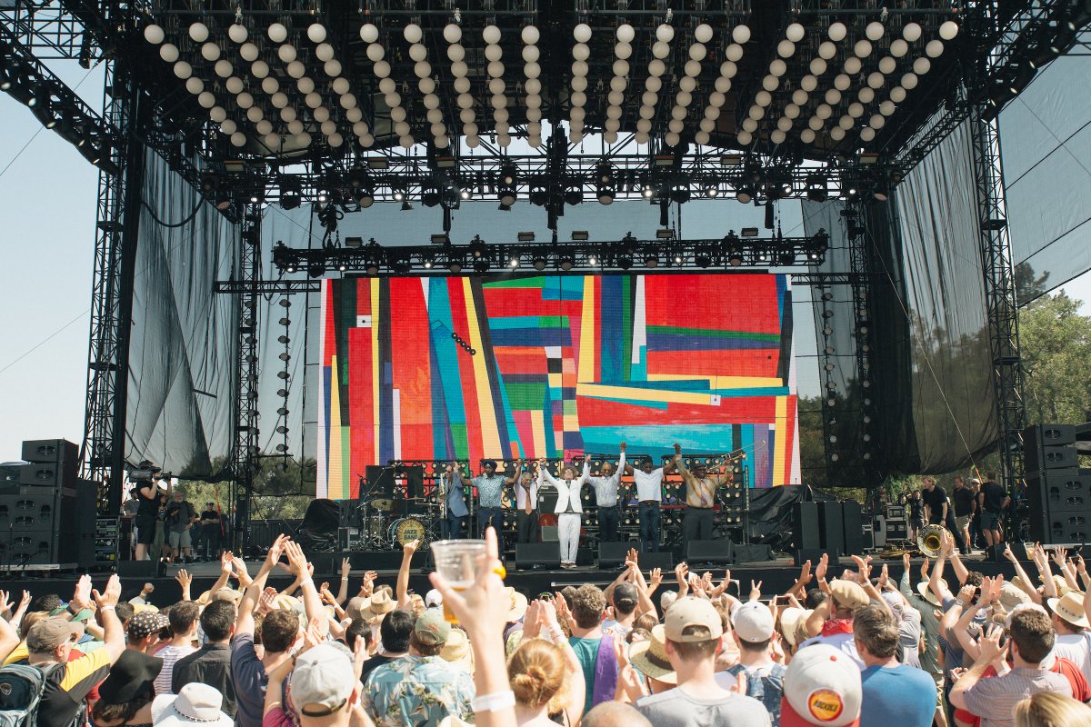 Image of a band on stage holding hands in the air after a set