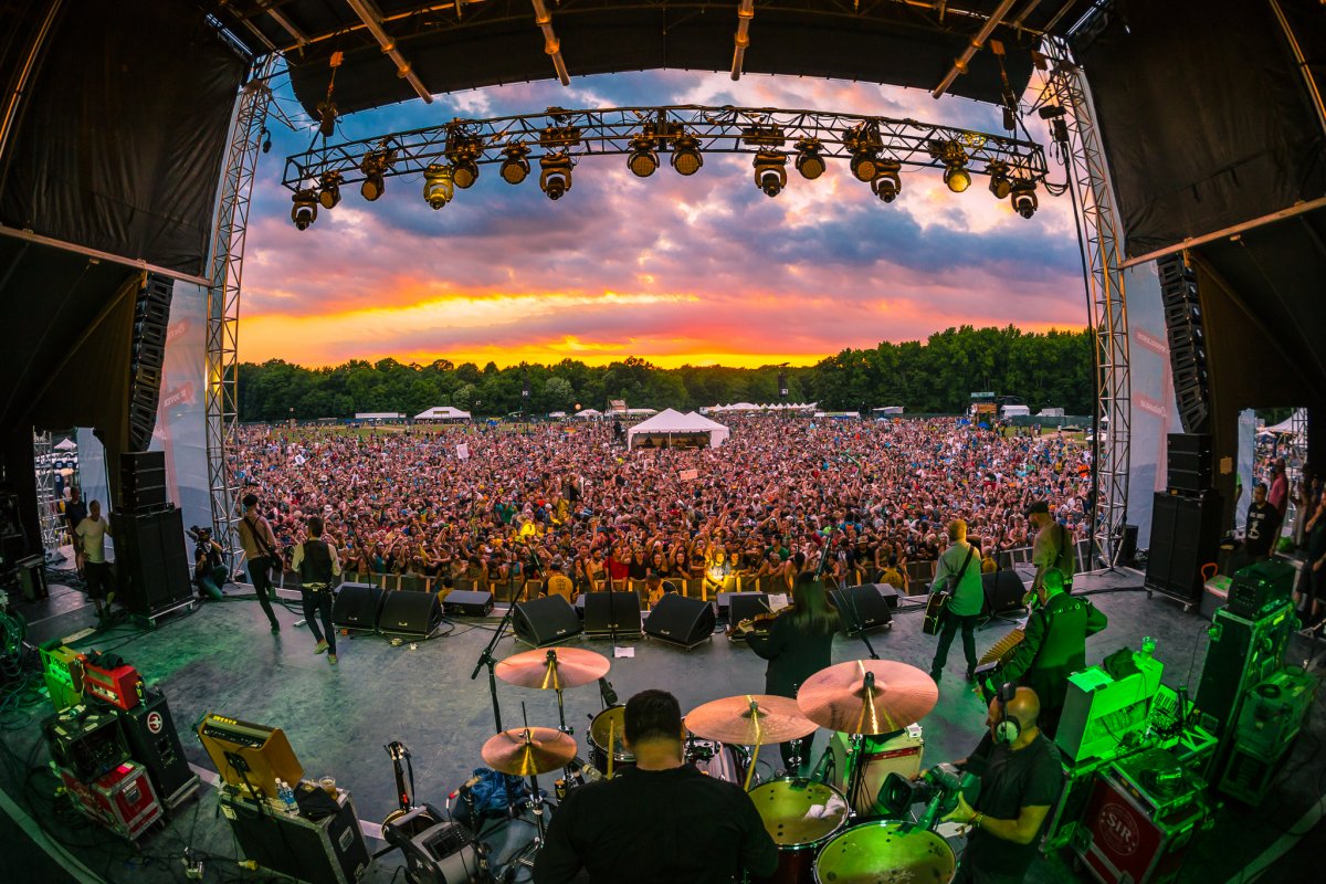 Image looking out into the crowd from behind performers on stage with a vibrant sunset at Firefly Music Festival