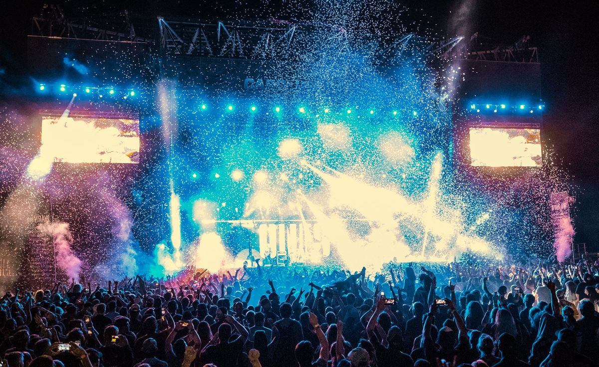 Image of lights coming from stage with crowd hands