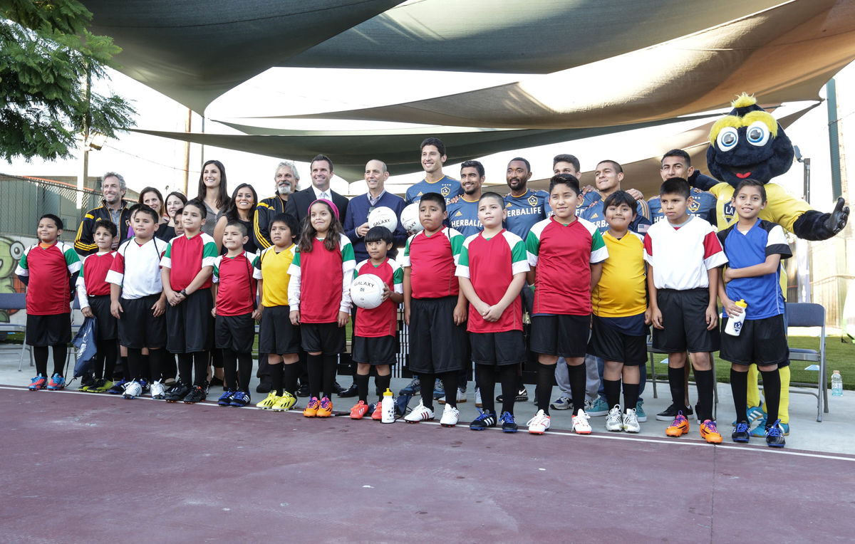 AEG’s LA Galaxy front office staff, players, team mascot Cozmo and youth athletes celebrate the LA Galaxy's installation of a new multipurpose sports field at A Place Called Home with a group photo in 2014.
