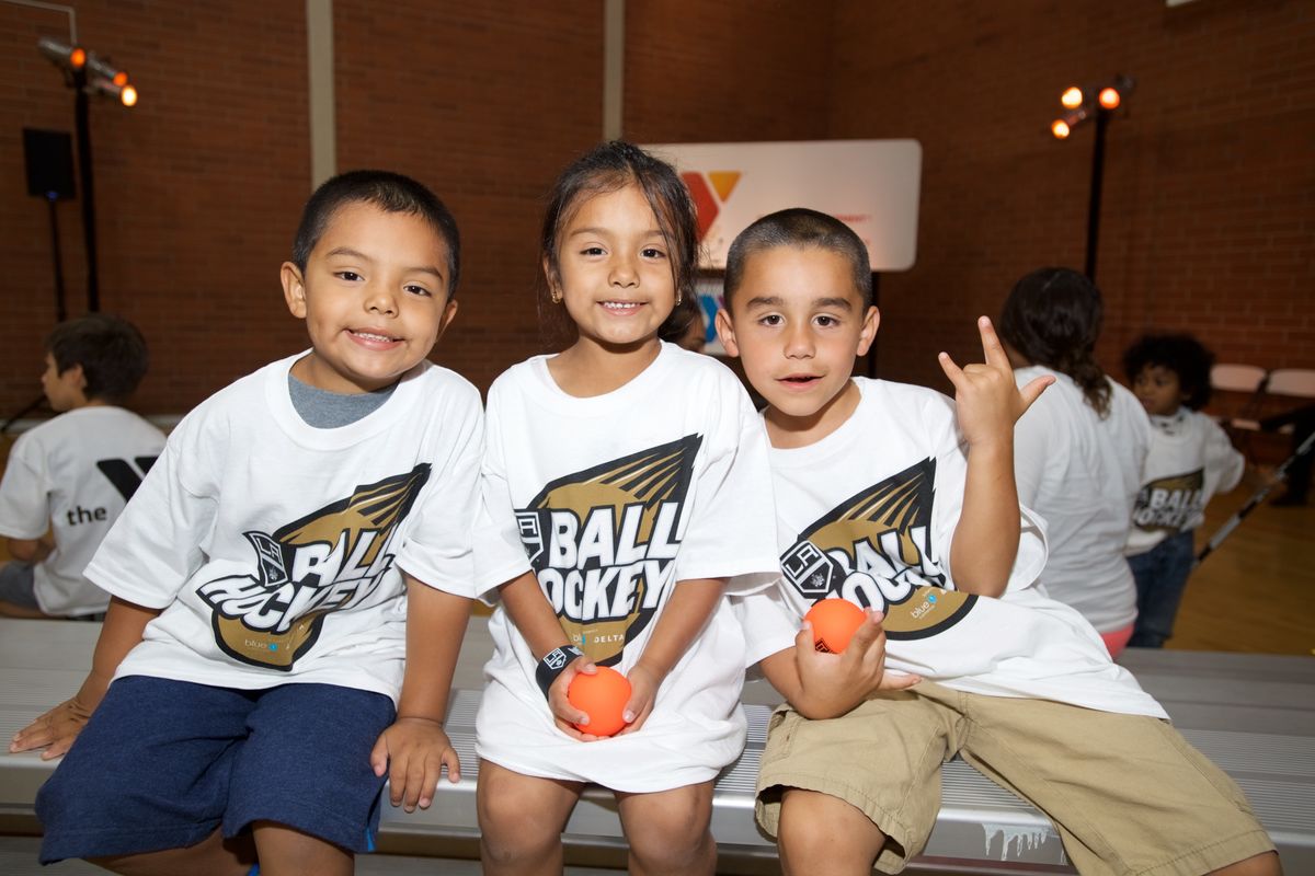 Three youth participants pose for a photo during the LA King’s Ball Hockey Clinic at a YMCA in the greater Los Angeles area.