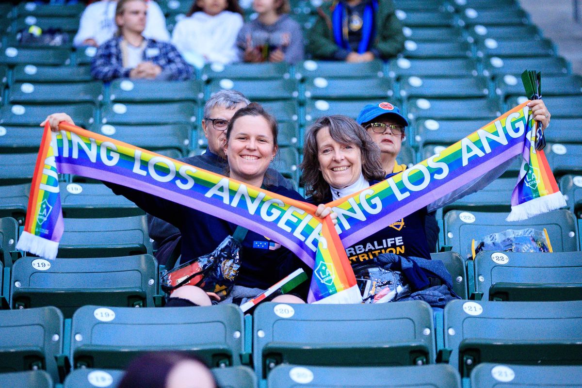 Two LA Galaxy fans hold up rainbow Galaxy scarves in the stands during the LA Galaxy's fifth annual Pride Night at StubHub Center on May 30, 2018.
