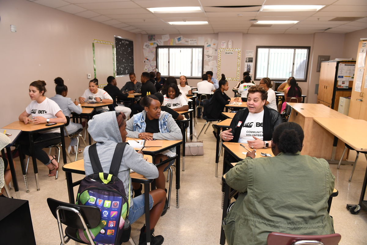High school students sit paired off with AEG and BET employees in a classroom to provide one-on-one mentoring and career advice. 