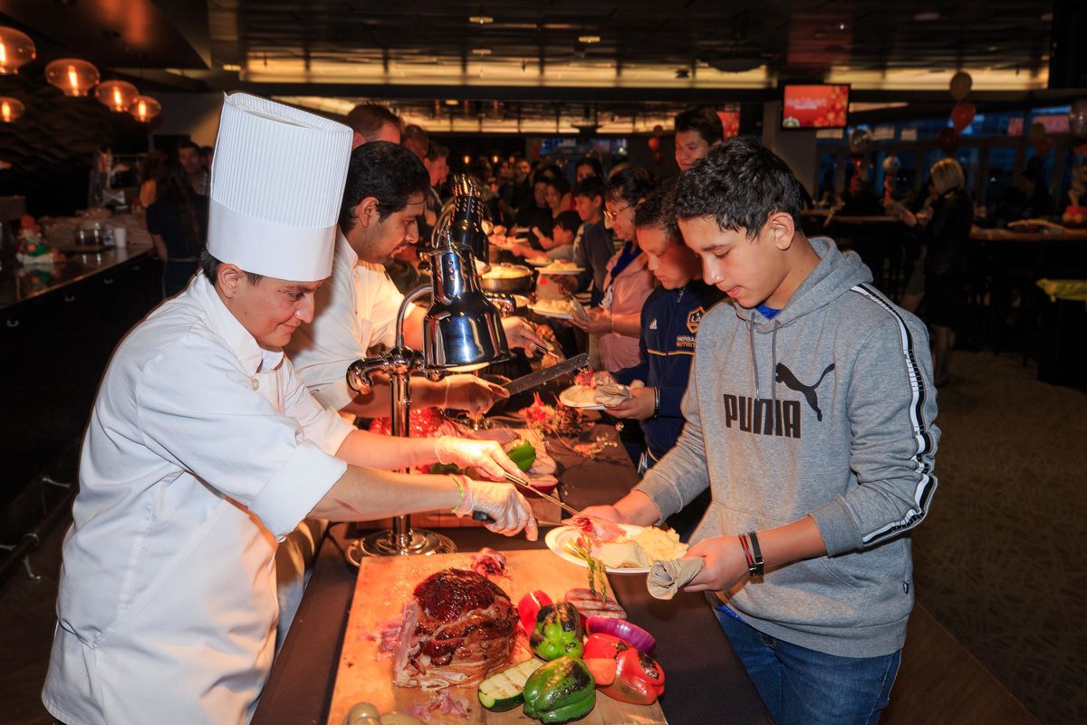 A chef carves a turkey and places a slice of meat on a child's plate during the buffet at the LA Galaxy and StubHub Center Foundations' Feast in Carson.