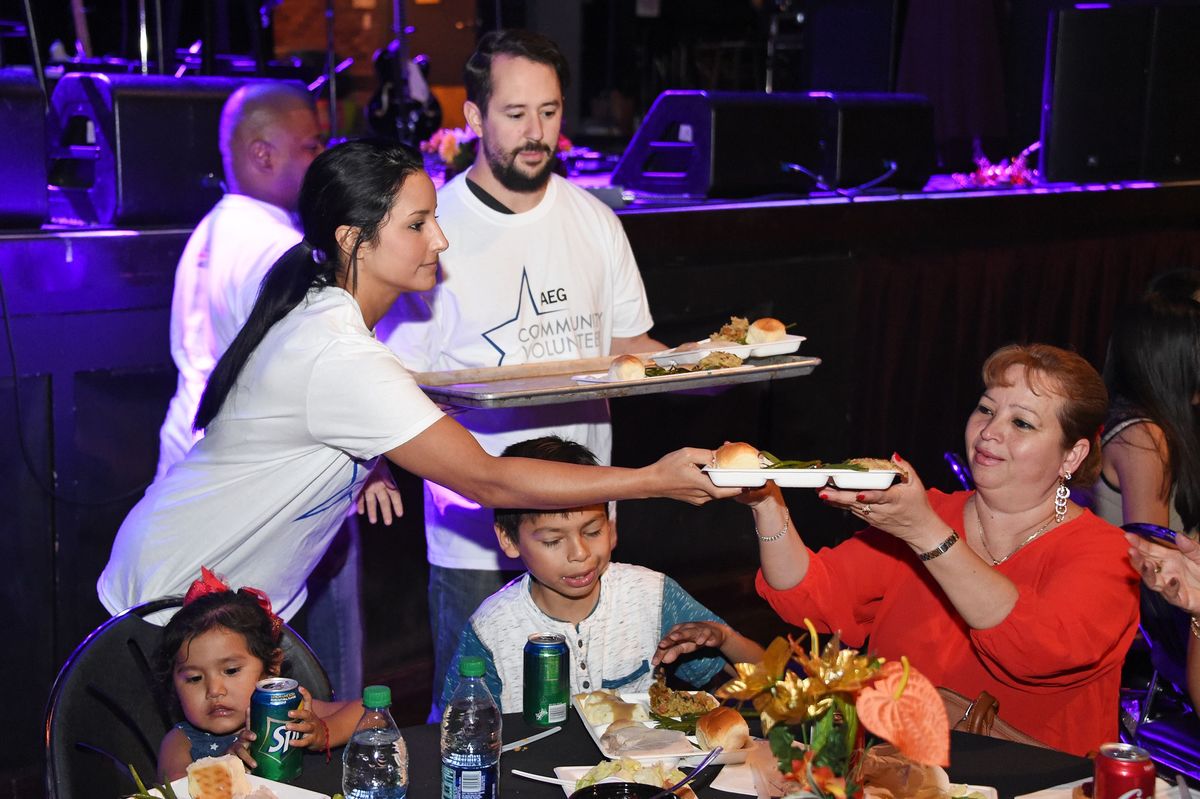 AEG community volunteers serve Thanksgiving meals to a family at The Novo at L.A. LIVE. 