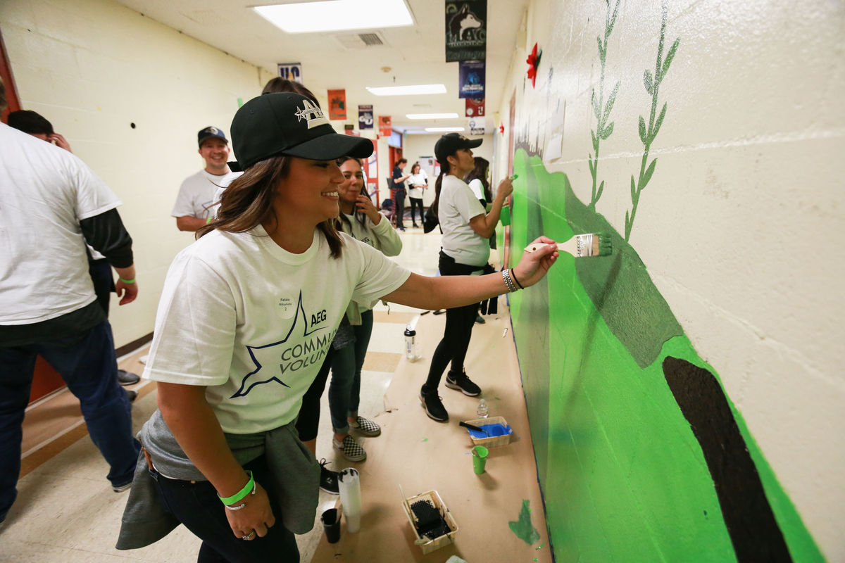 An AEG employee paints a design on the wall in a hallway at Magnolia Avenue Elementary for AEG's Annual Service Day.