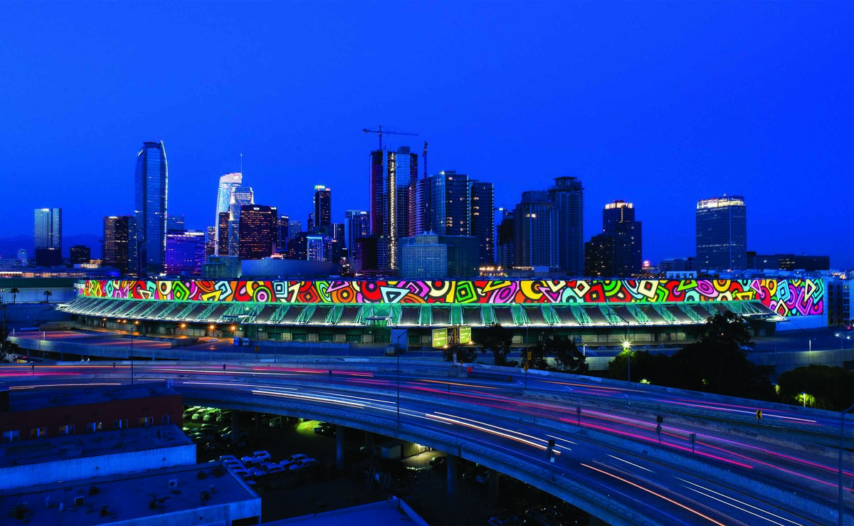 The Portraits of Hope art installation on the South Hall of the Los Angeles Convention Center is illuminated at night as cars pass by on the freeway. 