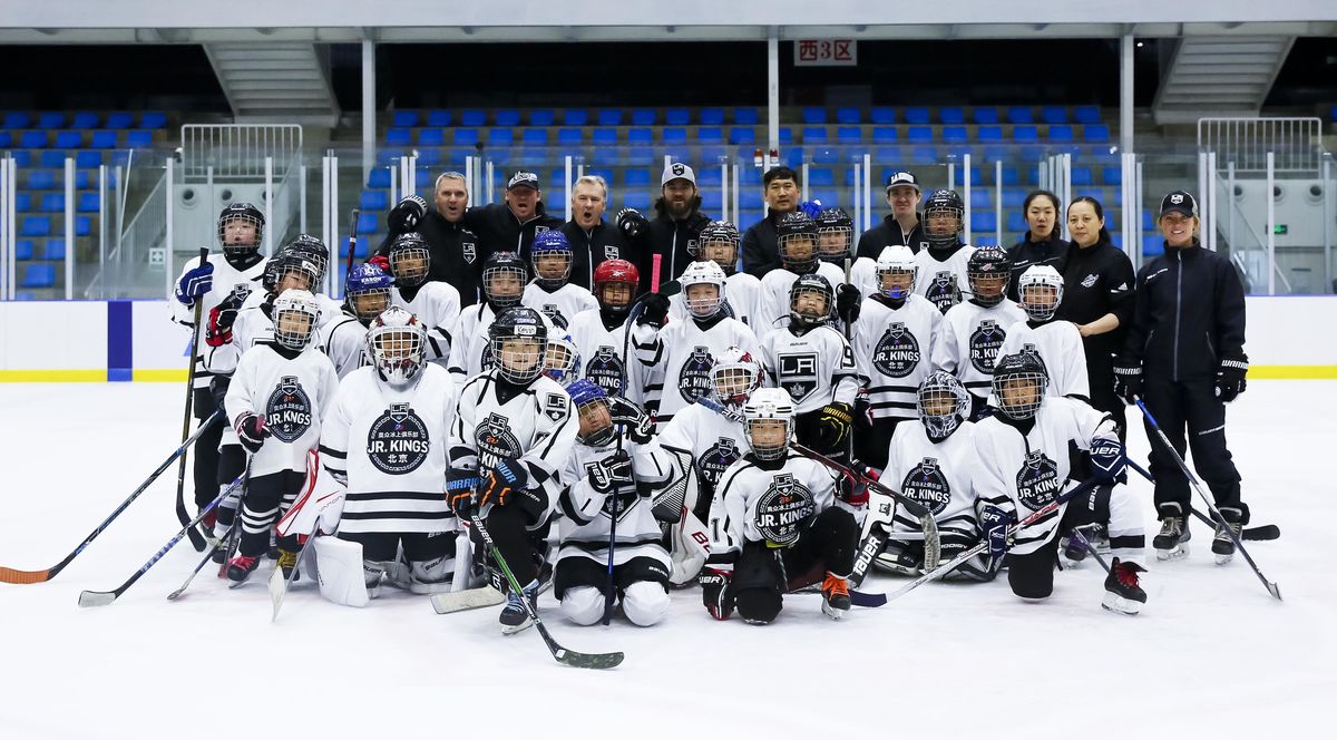 LA Kings hockey coaches and players ages 6-14 gather for a group photo on the ice in hockey gear.
