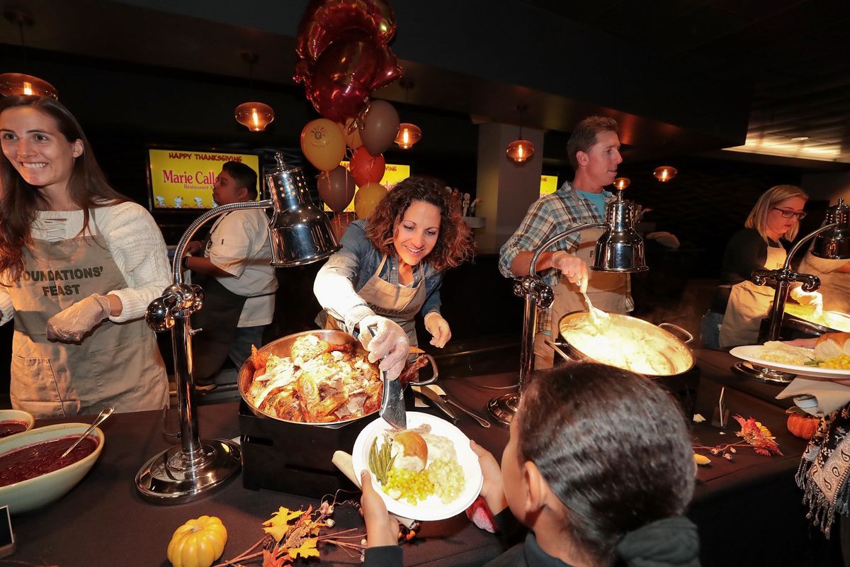 Dignity Health Sports Park General Manager Katie Pandolfo places a piece of turkey on a child's plate in the assembly line of the 16th annual LA Galaxy Foundation's Thanksgiving Feast.