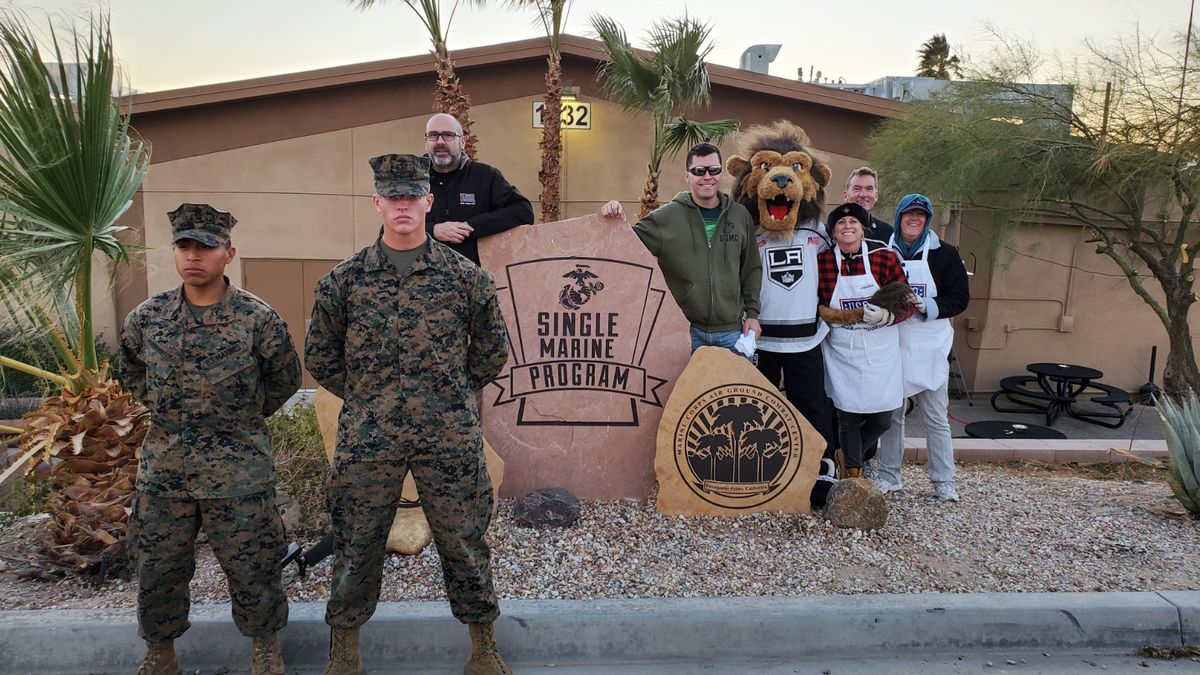 Two marines stand at attention in with LA Kings mascot Bailey and members of the USO during a watch party at the military training facility Twentynine Palms for Marines. 