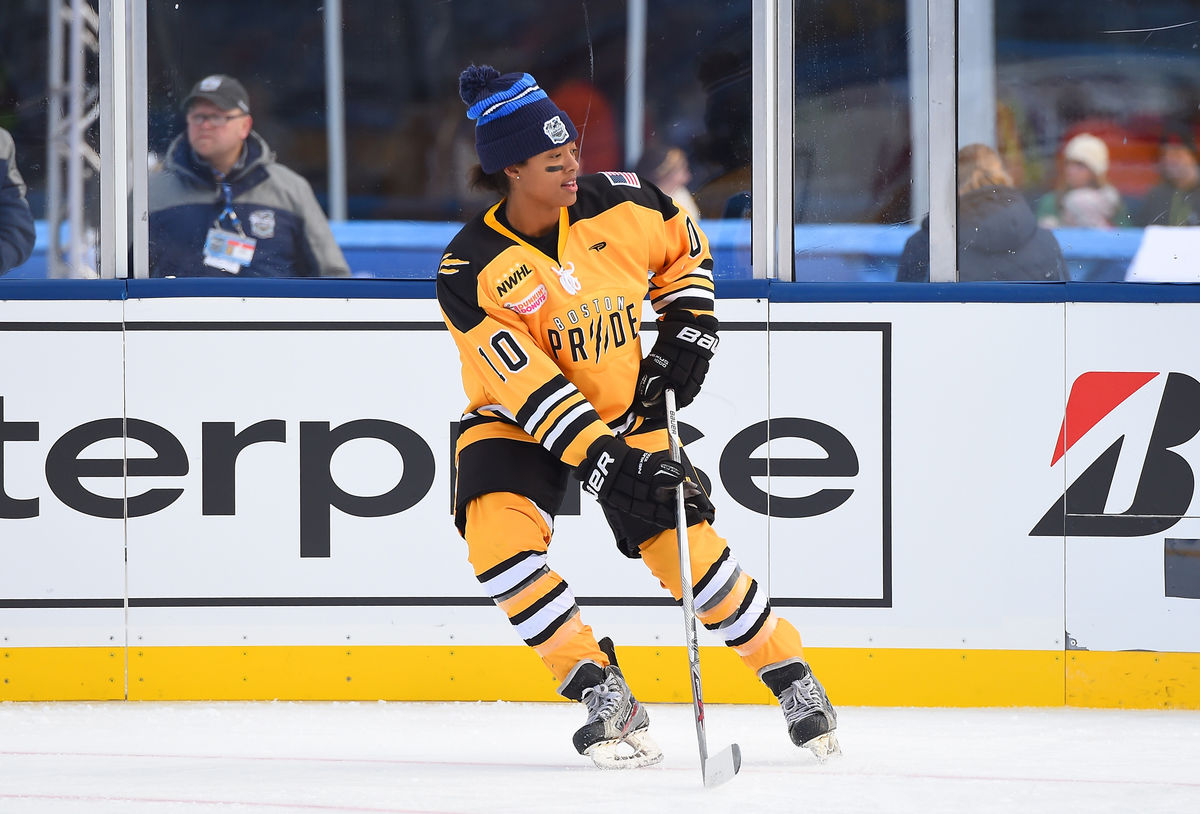 Blake Bolden skates on the ice in her yellow NWHL jersey. 