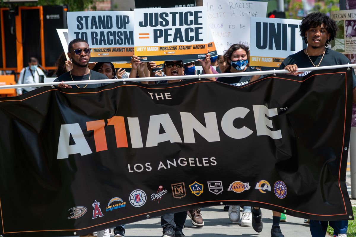 Students from Brotherhood Crusade carry a black banner with the words "The Alliance Los Angeles" in front of the Unity March Against Racism in Los Angeles. 