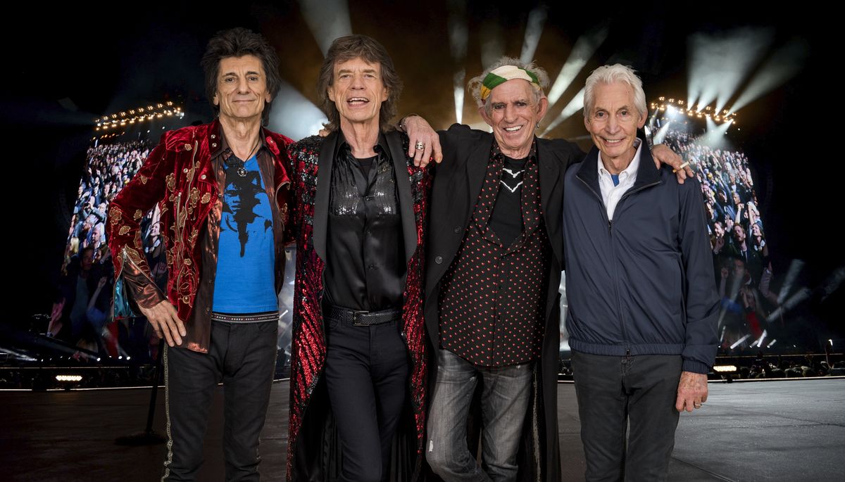 Members of the Rolling Stones pose for a group photos on stage. 