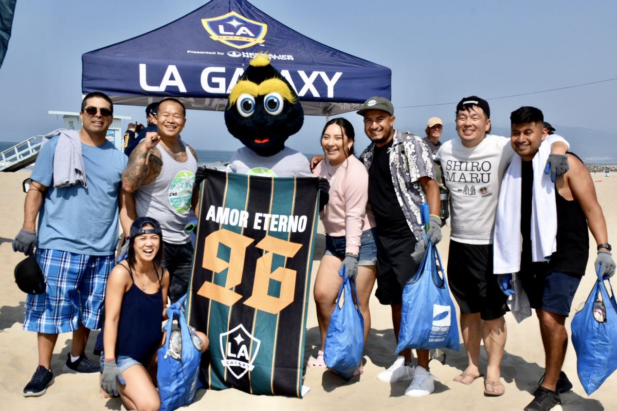 LA Galaxy Cozmo poses with LA Galaxy fans holding full trash bags during a beach cleanup at Venice Beach, CA. 
