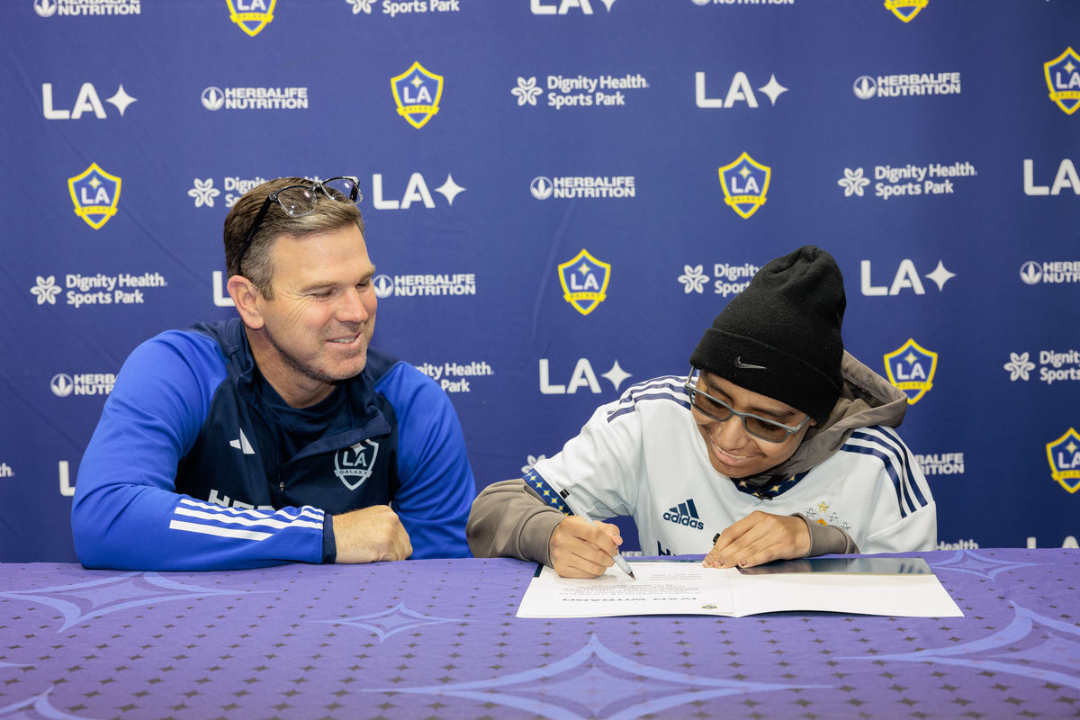 President of LA Galaxy Chris Klein watches as Ivan signs an honorary member contract.