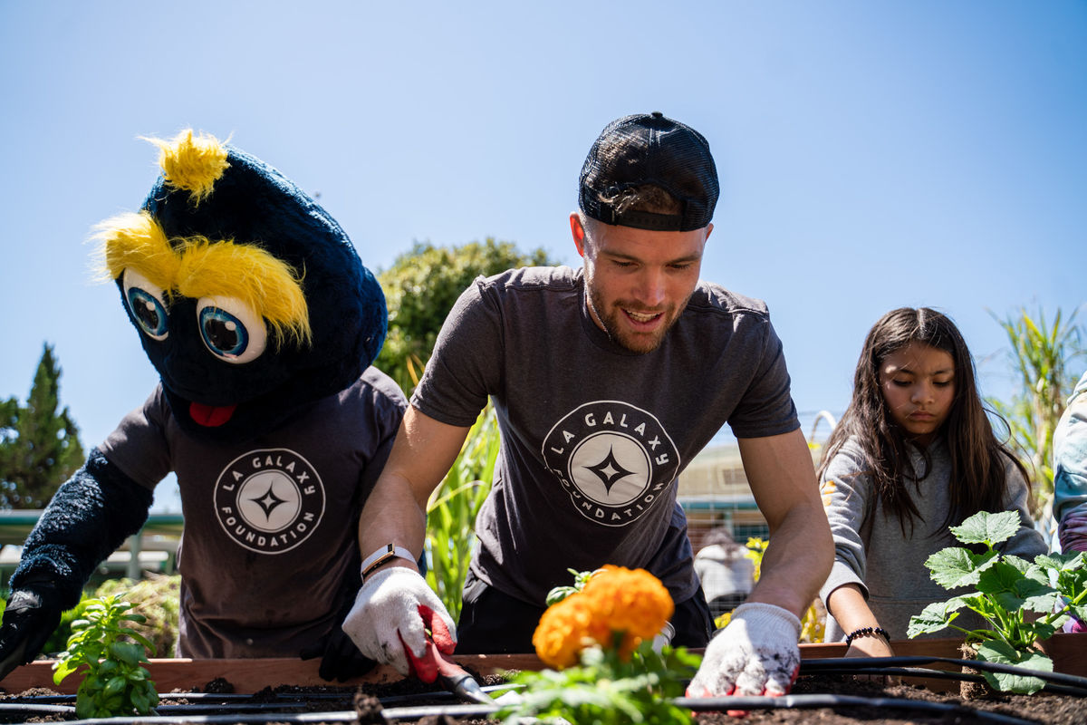 LA Galaxy's Eriq Zalaveta and mascot Cozmo join students for a gardening project at AnnaLee Elementary School in Carson, CA.